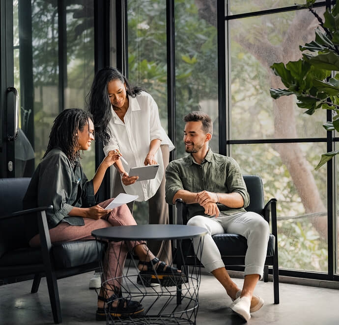 Três pessoas sorrindo, duas mulheres e um homem, segurando um tablet Três pessoas sorrindo, duas mulheres e um homem, segurando um tablet